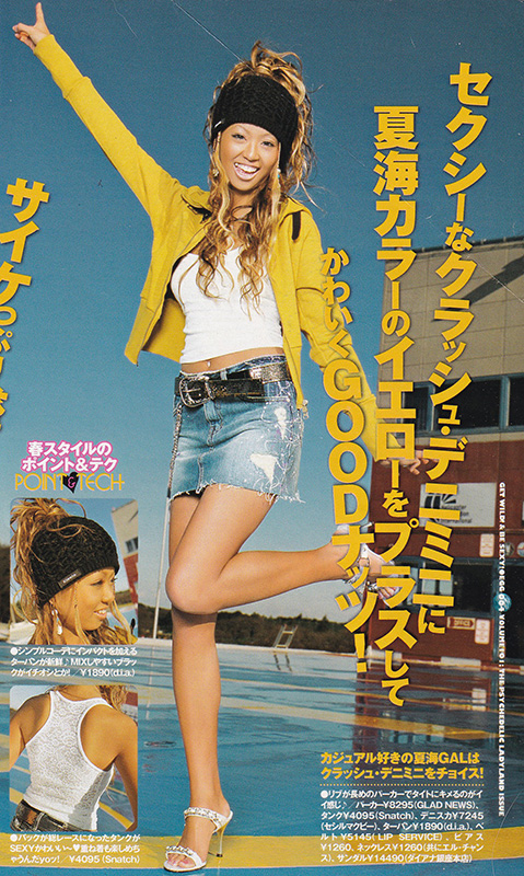 Photo of a Shibuya Gyaru wearing a yellow jacket and knit style beanie cap - smiling and pointing to the sky