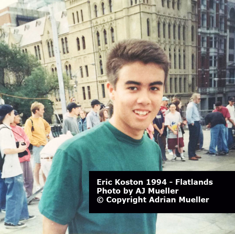 Portrait of Eric Koston smiling wearing with skaters 
                wearing 90s fashion and baggy jeans in the background.