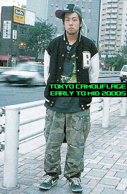 Photo of a man standing in Tokyo with b-boy style clothing. Nike hi-tops, a cap twisted to the side slightly 
    and baggy camouflage pants.