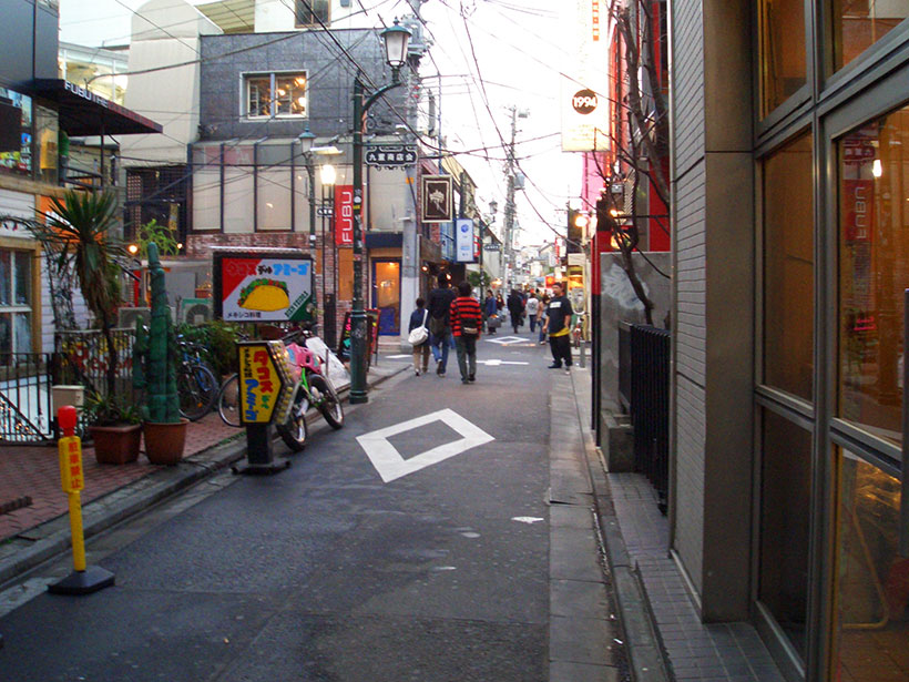 A photo I took from around a long time ago of a small side street in Harajuku with people wandering into
  the distance.