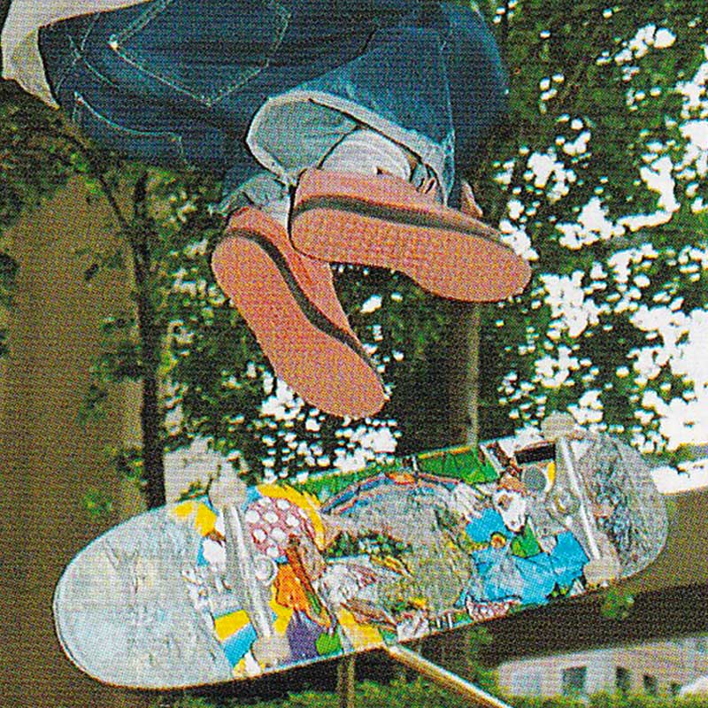 Close up of a photo of a skater wearing bright orange Puma Clyde
                            shoes with baggy cut off denim jeans - inflight above a skateboard while performing a trick.