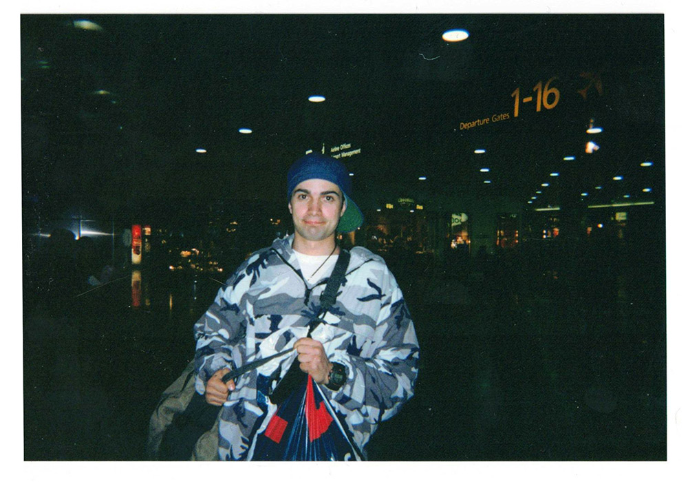 Photograph from the Early 2000s of Sean Kavanagh en route to Japan.
    He is wearing a blue denim cap backwards and loose 90s street style windbreaker.